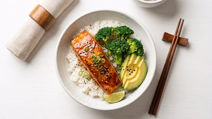 Honey sriracha glazed salmon fillet over white rice with avocado and vegetables
