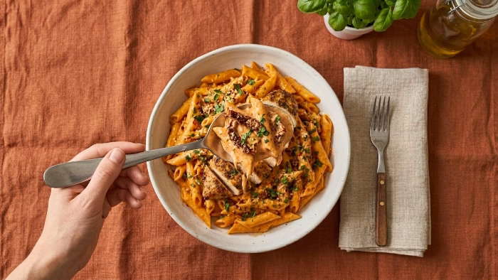 Serving Crockpot Marry Me Chicken Pasta garnished with basil