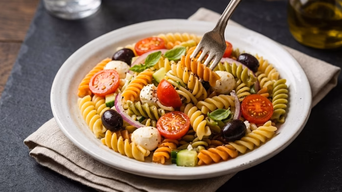 cold lunch spread with pasta salad, wraps and veggie bowls