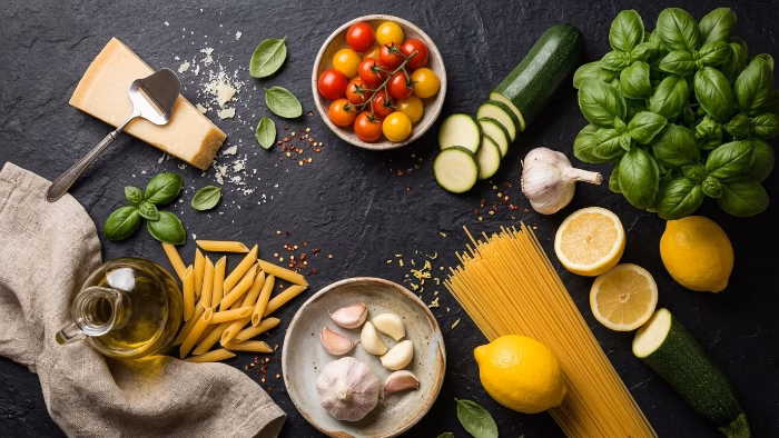 fresh ingredients for light pasta dishes: pasta, vegetables, lemons and olive oil